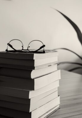 grayscale photography of eyeglasses on books